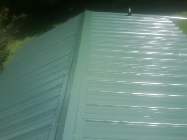 New green metal panels meeting at the ridge of a roof — Flat Roof Repair work by our crew in Cedarville