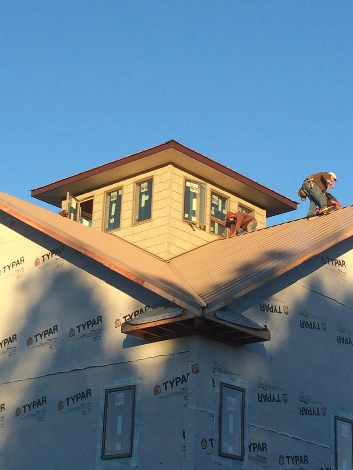 Roofers working around a rooftop cupola on a new metal roof at sunset — Roof Waterproofing in Cedarville by Roofing Brothers